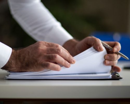 Male arm in suit offer insurance form clipped to pad